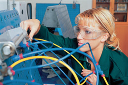 a woman wearing safety goggles interacting with a piece of equipment