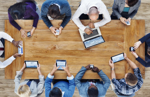 an overhead shot of a group of people working at a table on various devices