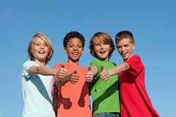four kids standing together giving a thumbs up